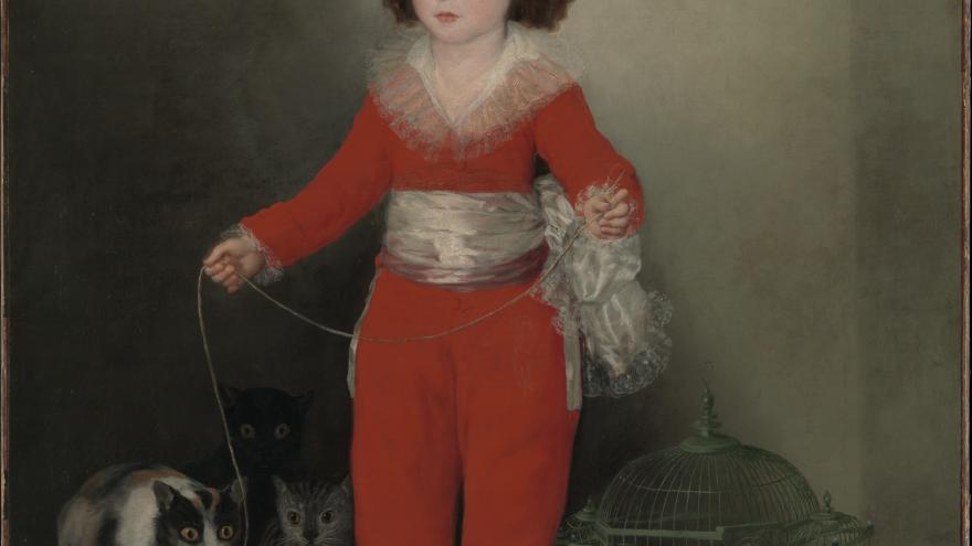 Child in red outfit holding a string tied to a bird, standing with pets