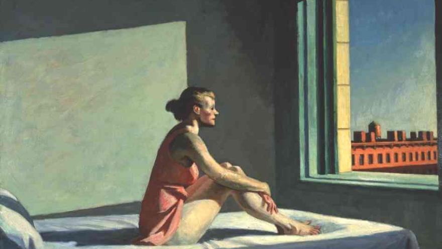 Woman sitting on a bed by a window