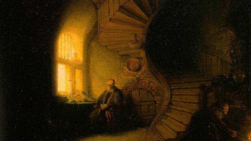 Figure seated by a window with a spiral staircase in dim lighting