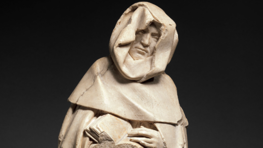 Stone sculpture of a cloaked figure holding a book